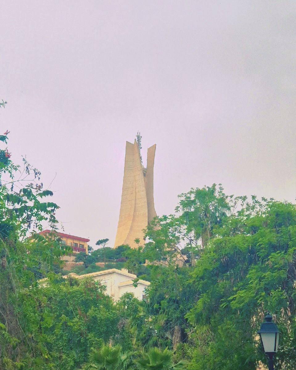 Le monument des Martyrs d'Alger, haute sculpture de béton beige, au-dessus de la végétation