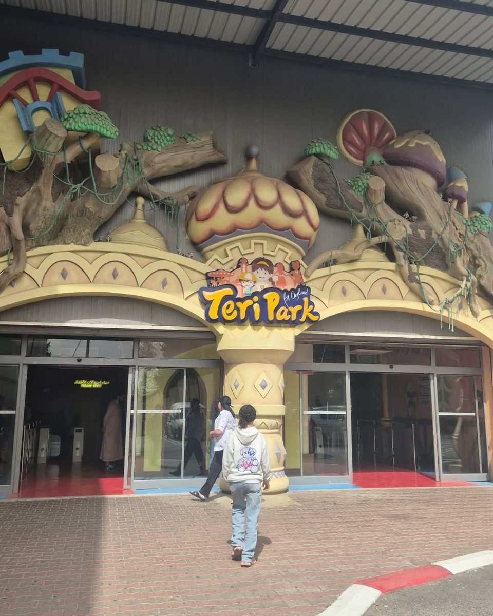 L'entrée colorée du parc de jeux couvert Teri Park à Alger, décorée de dômes et de troncs d'arbres sculptés, avec un enfant vu de dos