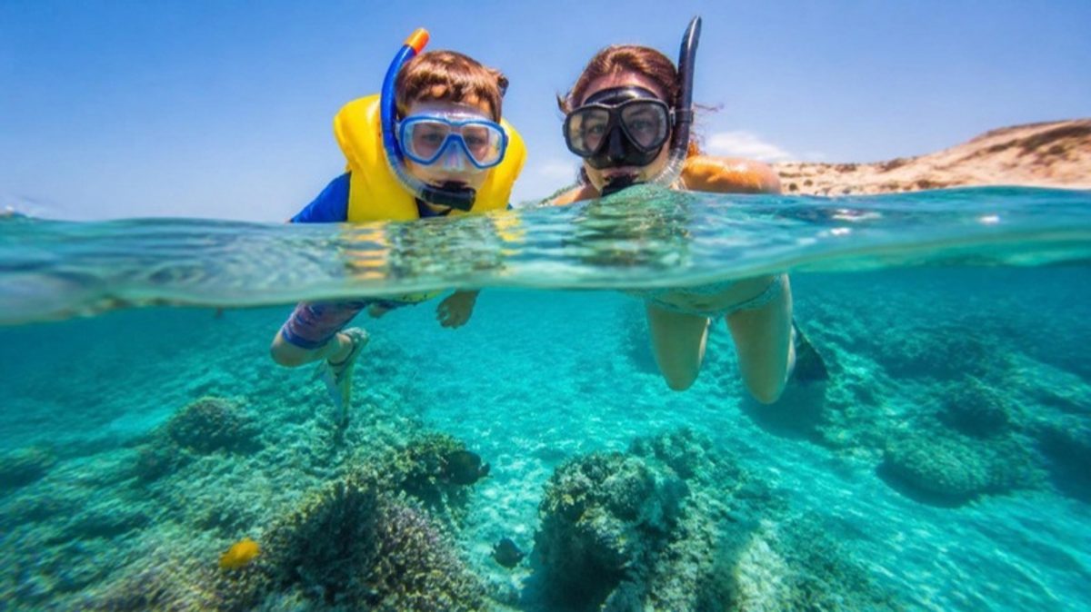 Une mère et son fils en masque et tuba au-dessus d'un récif de corail en mer Rouge