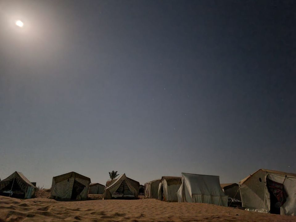 Des tentes de campement dans le désert, de nuit, sous la lune