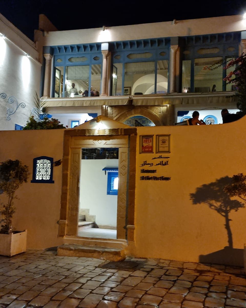 Une maison aux murs ocre et aux fenêtres bleues, éclairée la nuit