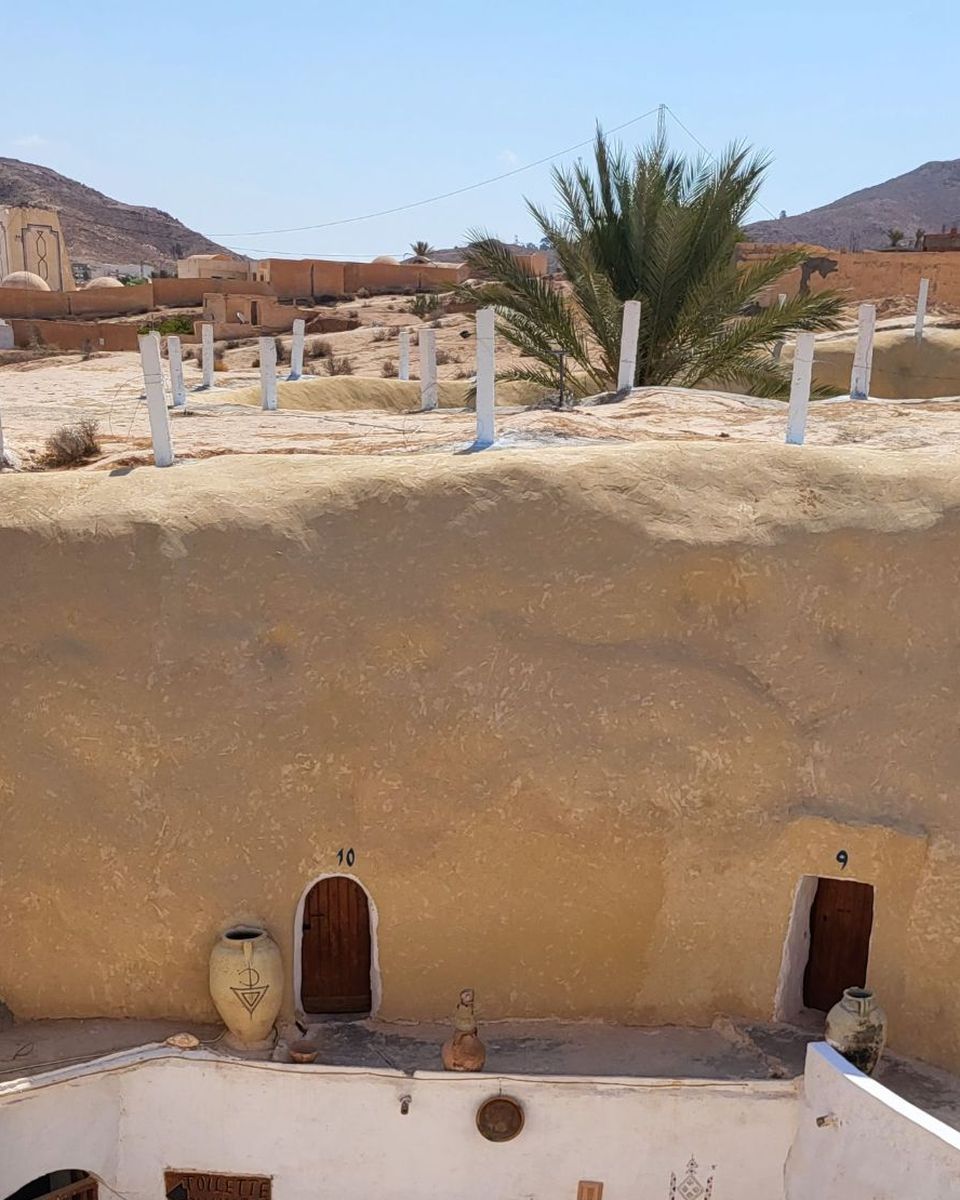 La cour creusée de l'hôtel Sidi Idriss, avec ses portes en bois numérotées taillées dans la paroi et des jarres