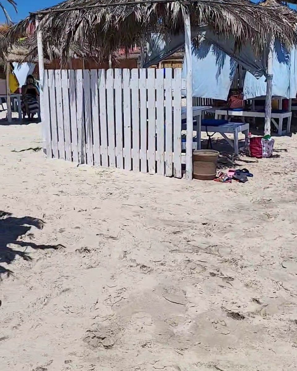Une paillote en palmes et une barrière blanche sur une plage de sable fin